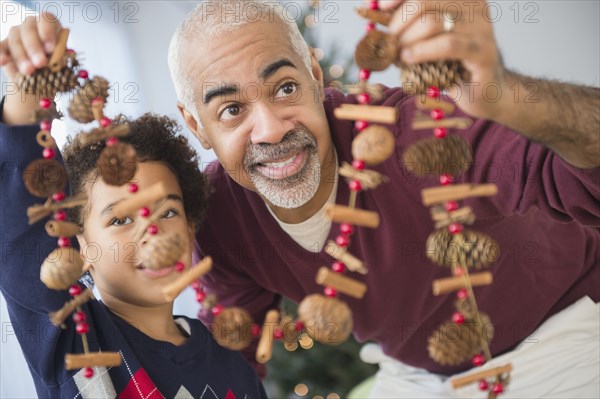 Mixed race grandfather and grandson holding Christmas decorations