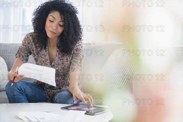 Mixed race woman paying bills on digital tablet