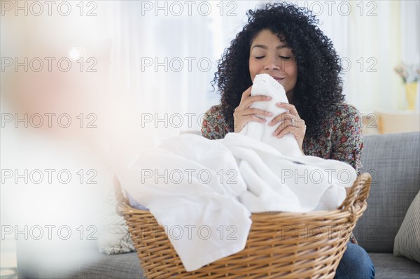 Mixed race woman smelling clean towels in laundry