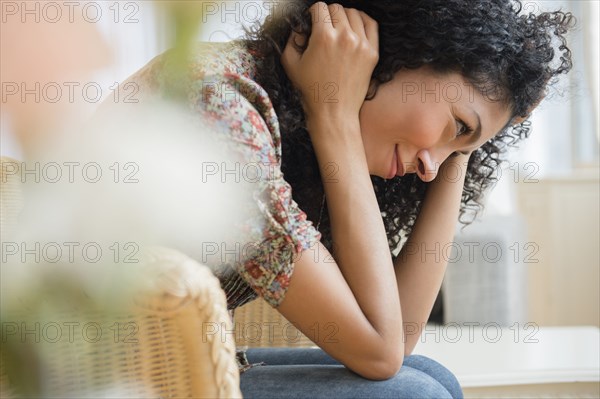 Mixed race woman sitting in wicker chair