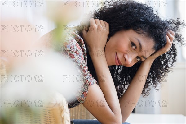 Mixed race woman sitting in wicker chair