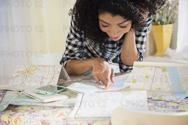 Mixed race woman planning road trip with maps