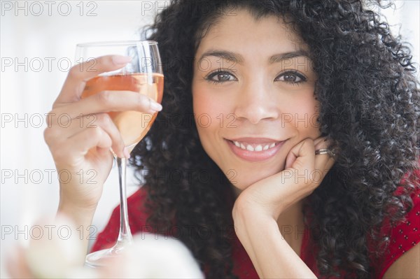 Mixed race woman drinking glass of wine