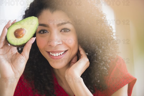 Mixed race woman holding avocado half