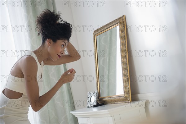 Mixed race woman styling hair in mirror