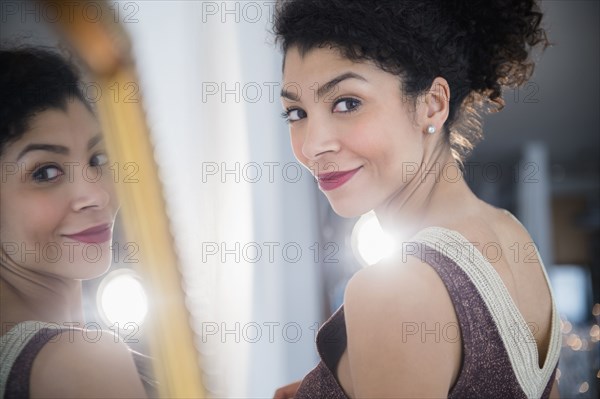 Mixed race woman wearing evening gown near mirror