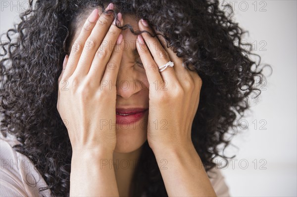 Mixed race woman with curly hair covering her face