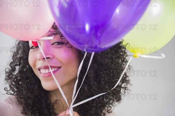 Mixed race woman holding bunch of balloons