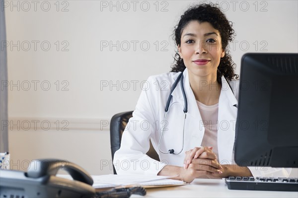 Mixed race doctor sitting at desk in office