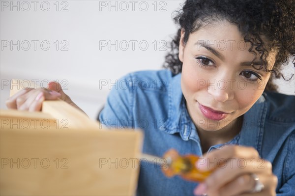 Mixed race woman assembling furniture