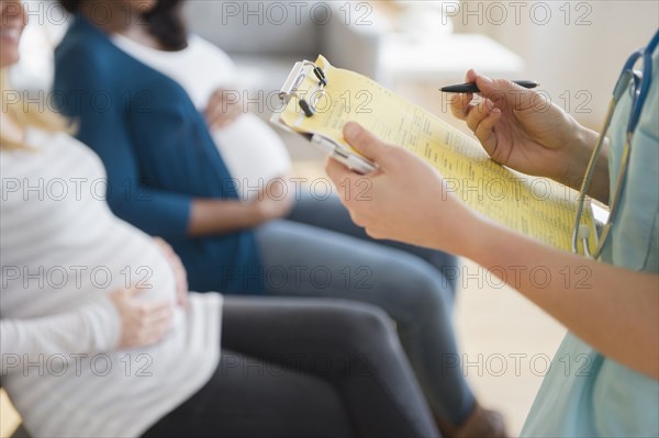 Nurse marking medical chart near pregnant women