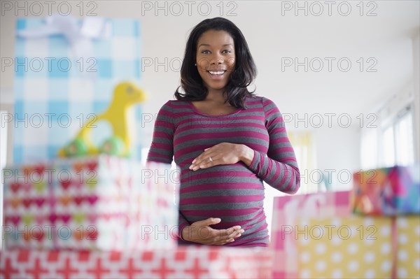 Black pregnant woman admiring gifts at baby shower