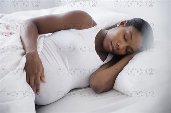 Black pregnant woman sleeping in bed