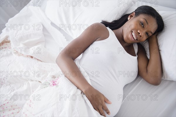 Black pregnant woman smiling in bed