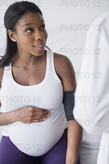 Doctor checking blood pressure of Black pregnant woman