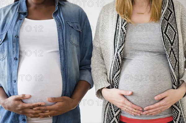 Close up of pregnant women holding stomachs