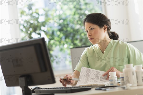 Mixed race nurse working on computer in hospital