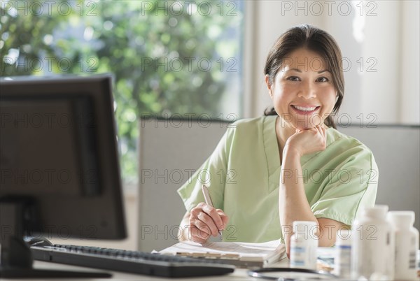 Mixed race nurse posing with computer in hospital