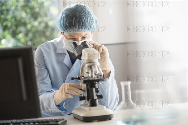 Mixed race scientist using microscope in laboratory