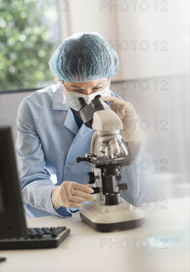 Mixed race scientist using microscope in laboratory