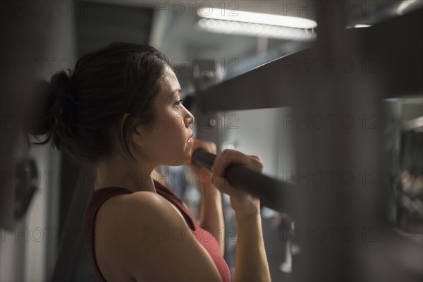 Mixed race woman using exercise machine in gym