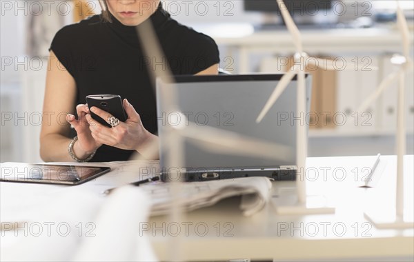 Mixed race architect with windmill models using cell phone