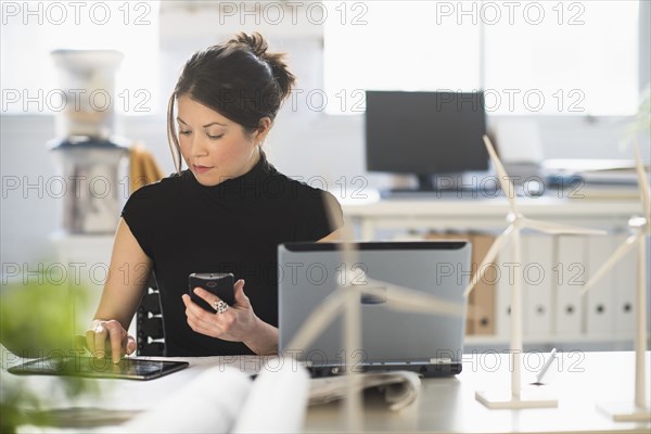 Mixed race architect with windmill models using digital tablet