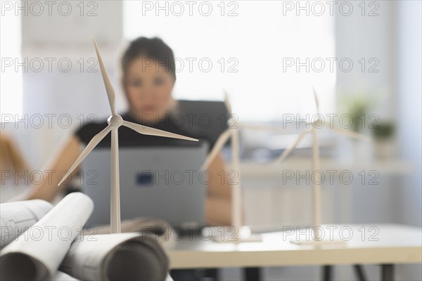 Mixed race architect with windmill models using laptop