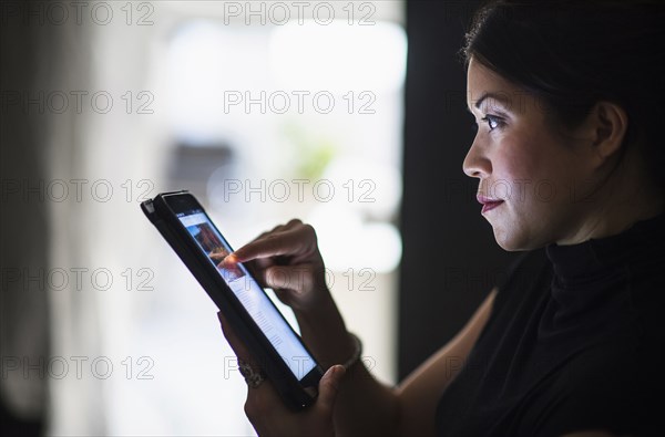 Mixed race woman using digital tablet at night