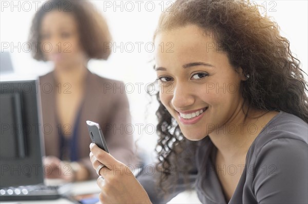 Businesswoman smiling with cell phone in office