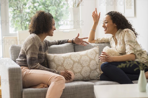 Laughing women talking on sofa