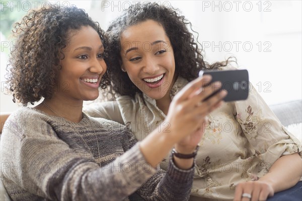 Smiling women taking cell phone photograph