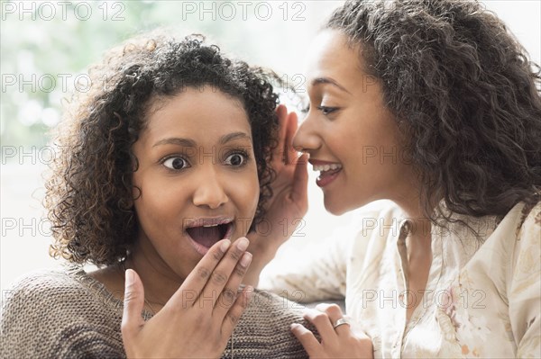 Surprised women whispering secrets