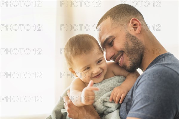 Father drying baby son with towel after bath