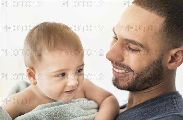 Father drying baby son with towel after bath