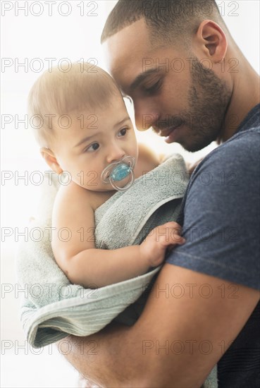 Father drying baby son with towel after bath