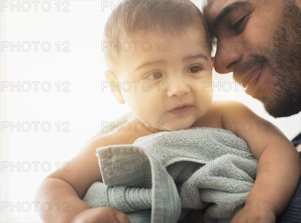 Father drying baby son with towel after bath