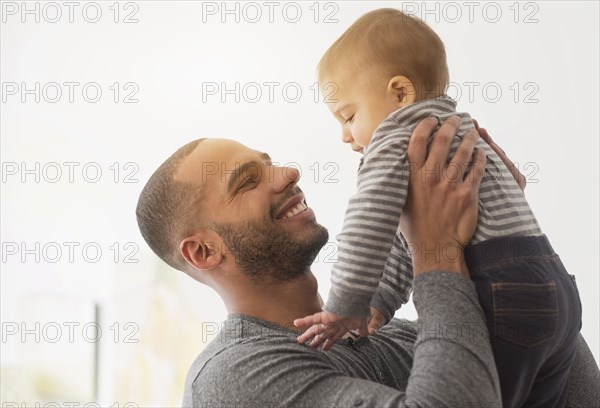 Smiling father playing with baby son