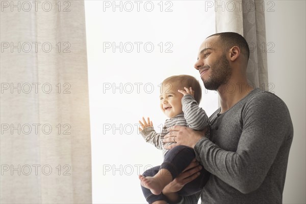 Smiling father and baby son looking out window