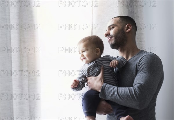 Smiling father and baby son looking out window