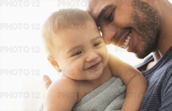 Father drying baby son with towel after bath