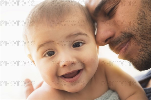 Father holding baby son in towel after bath