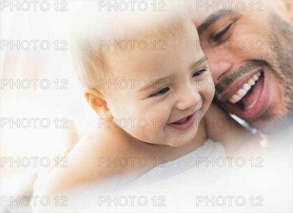 Father holding baby son in towel after bath