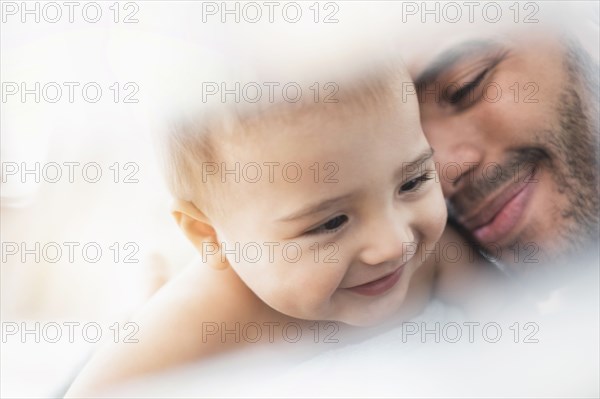 Father holding baby son in towel after bath
