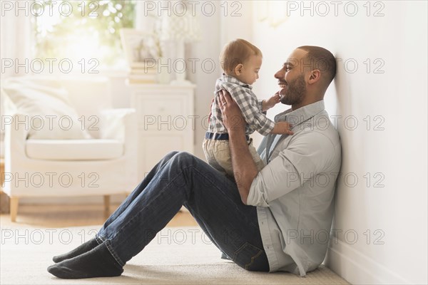 Father playing with baby son on floor