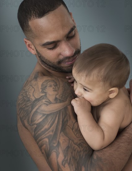 Father with tattoos holding baby son