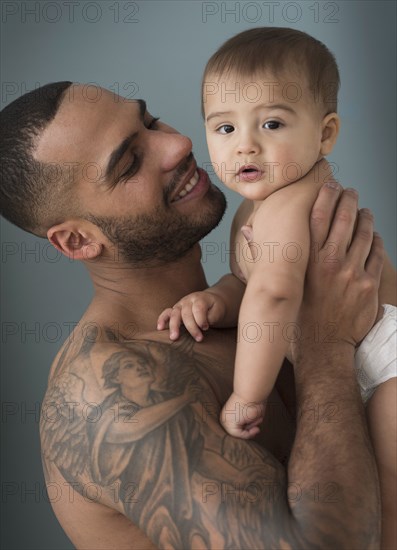 Father with tattoos holding baby son