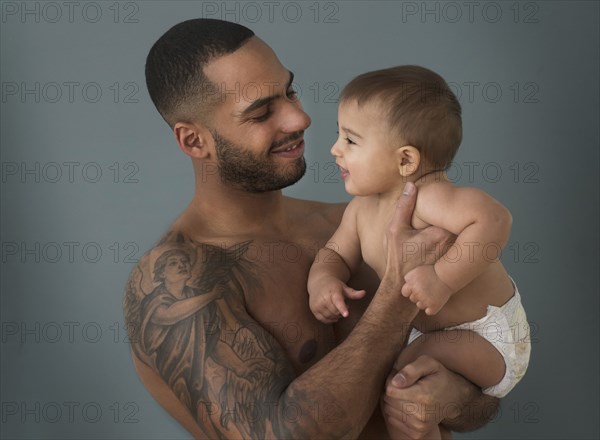 Father with tattoos holding baby son