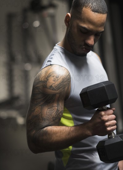 Close up of Hispanic man lifting weights in gym