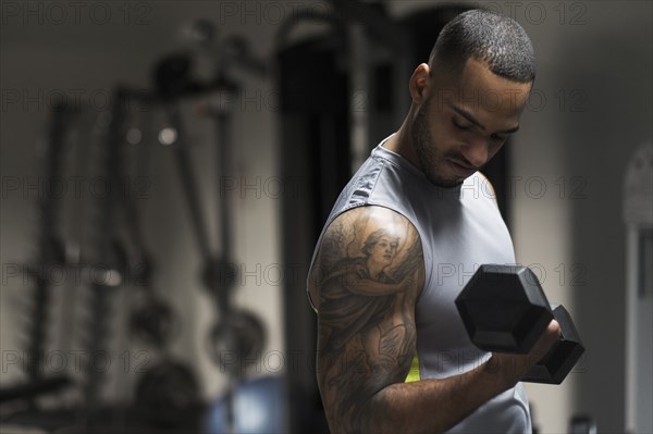 Close up of Hispanic man lifting weights in gym